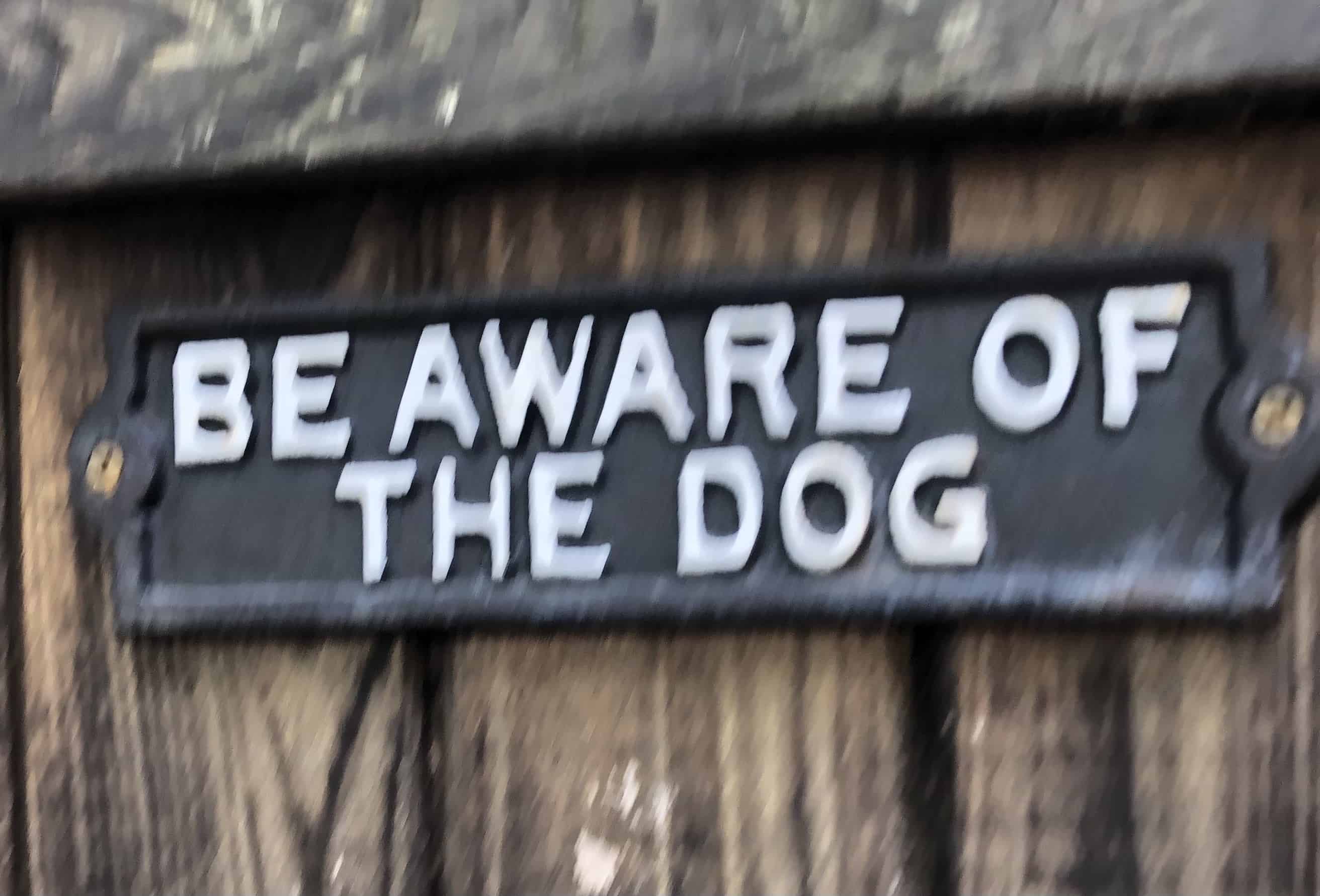 A yard sign reading "be aware of the dog."