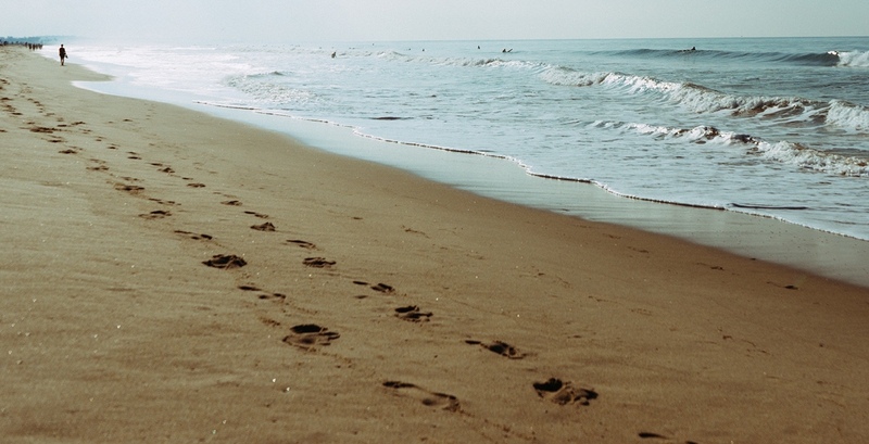 People leaving imprints, aka footprints, behind on a beach.